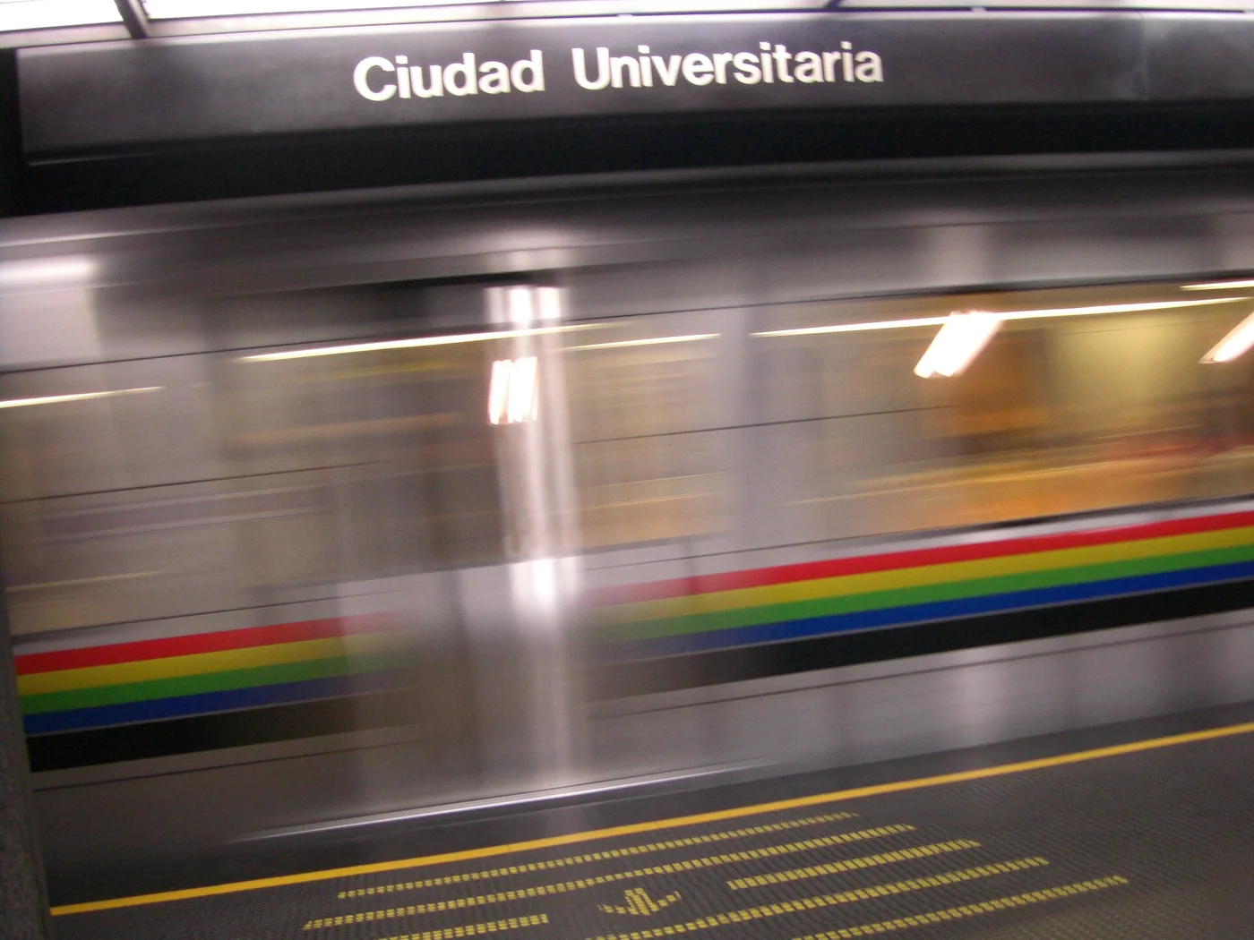 Ciudad Universitaria sign and a moving Caracas Metro train.