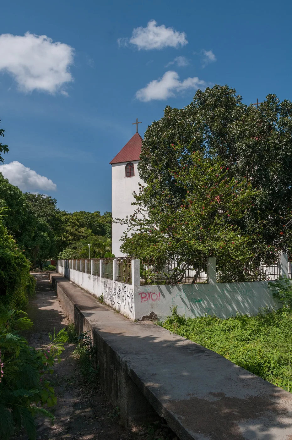 White church tower beside an open concrete drainage channel in Las Cabreras, Margarita Island.