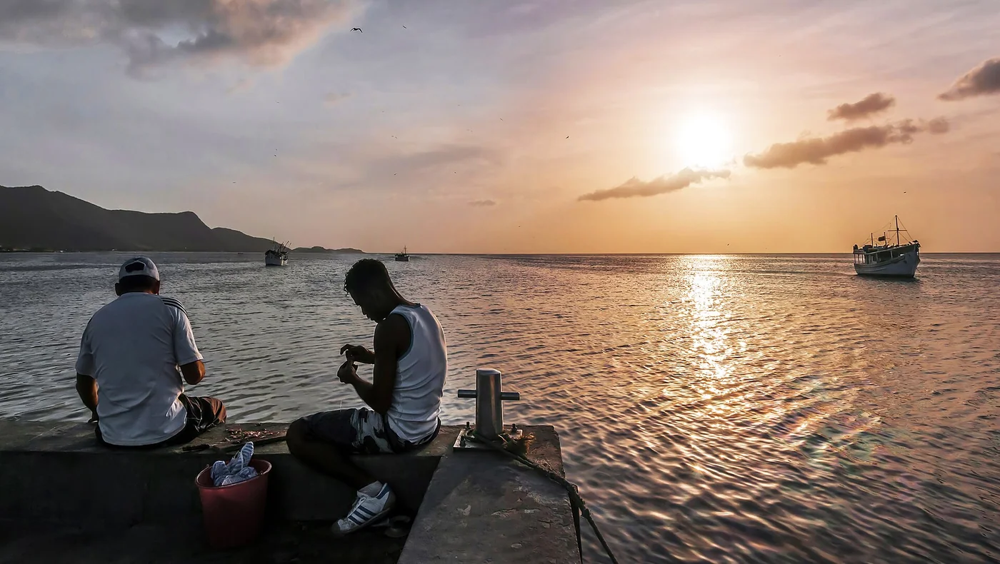 Two fishermen sitting together at sunset on the pier at Juan Griego, Margarita Island.