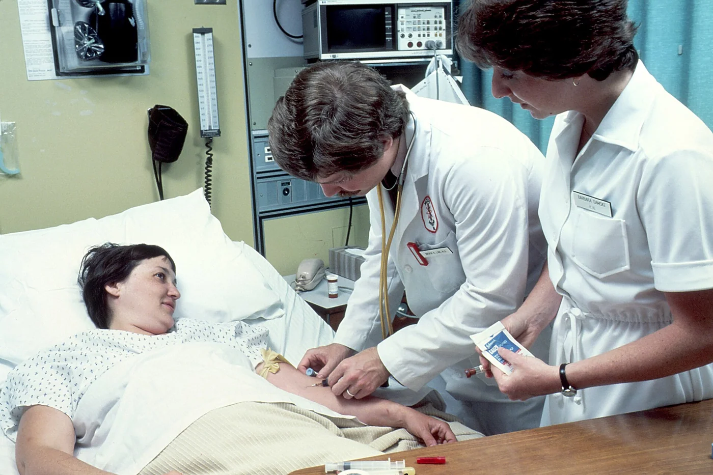 National Cancer Institute doctor drawing blood from a patient with a nurse attending