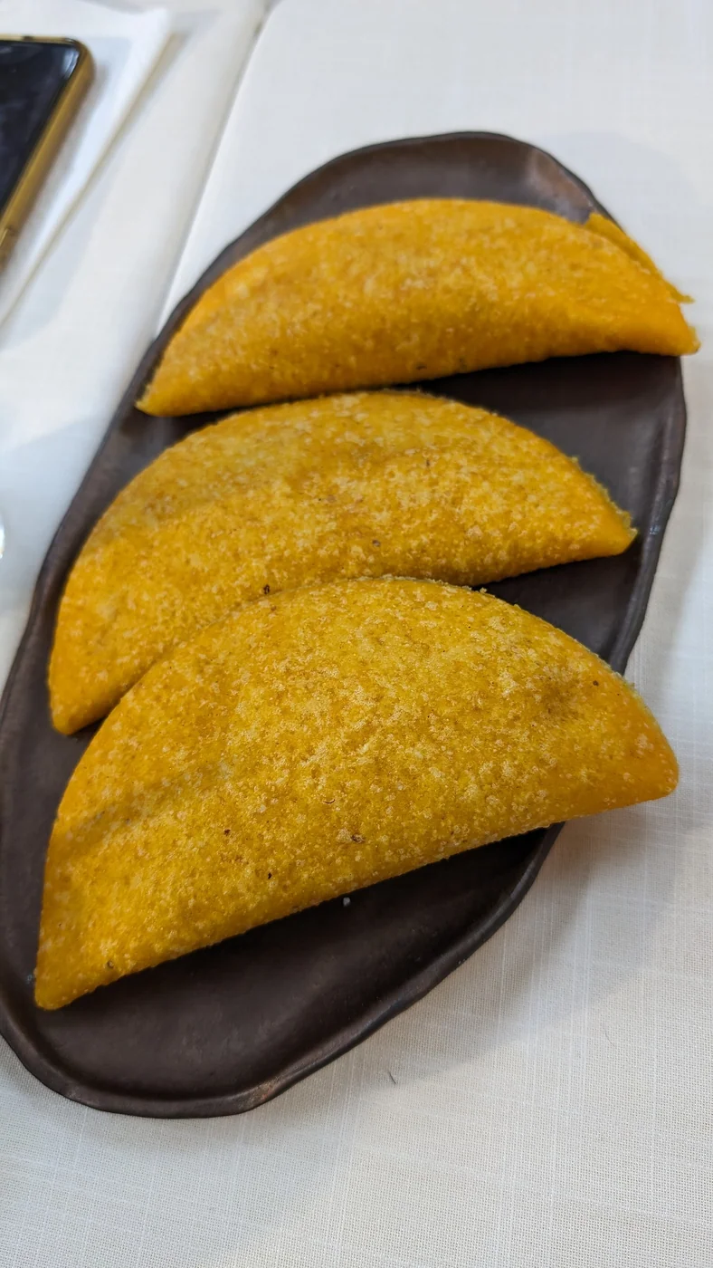 Three Venezuelan empanadas made from corn dough on a serving plate