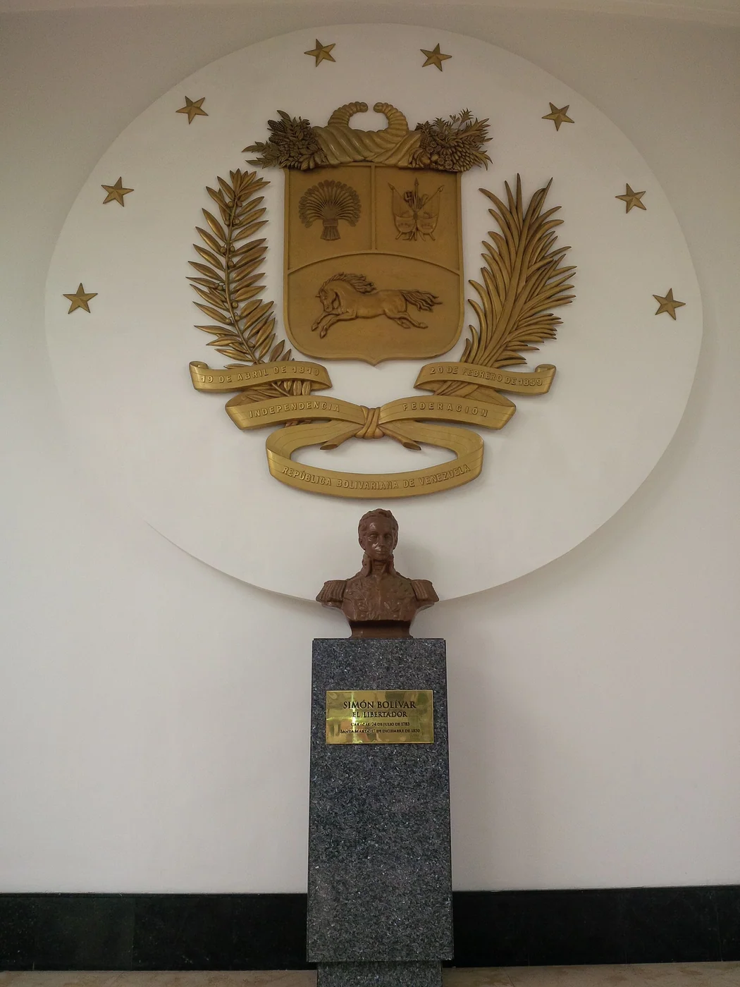 Coat of arms of Venezuela and bust of the Liberator Simon Bolivar in the inner garden of the Federal Legislative Palace in the historic center of Caracas, Venezuela
