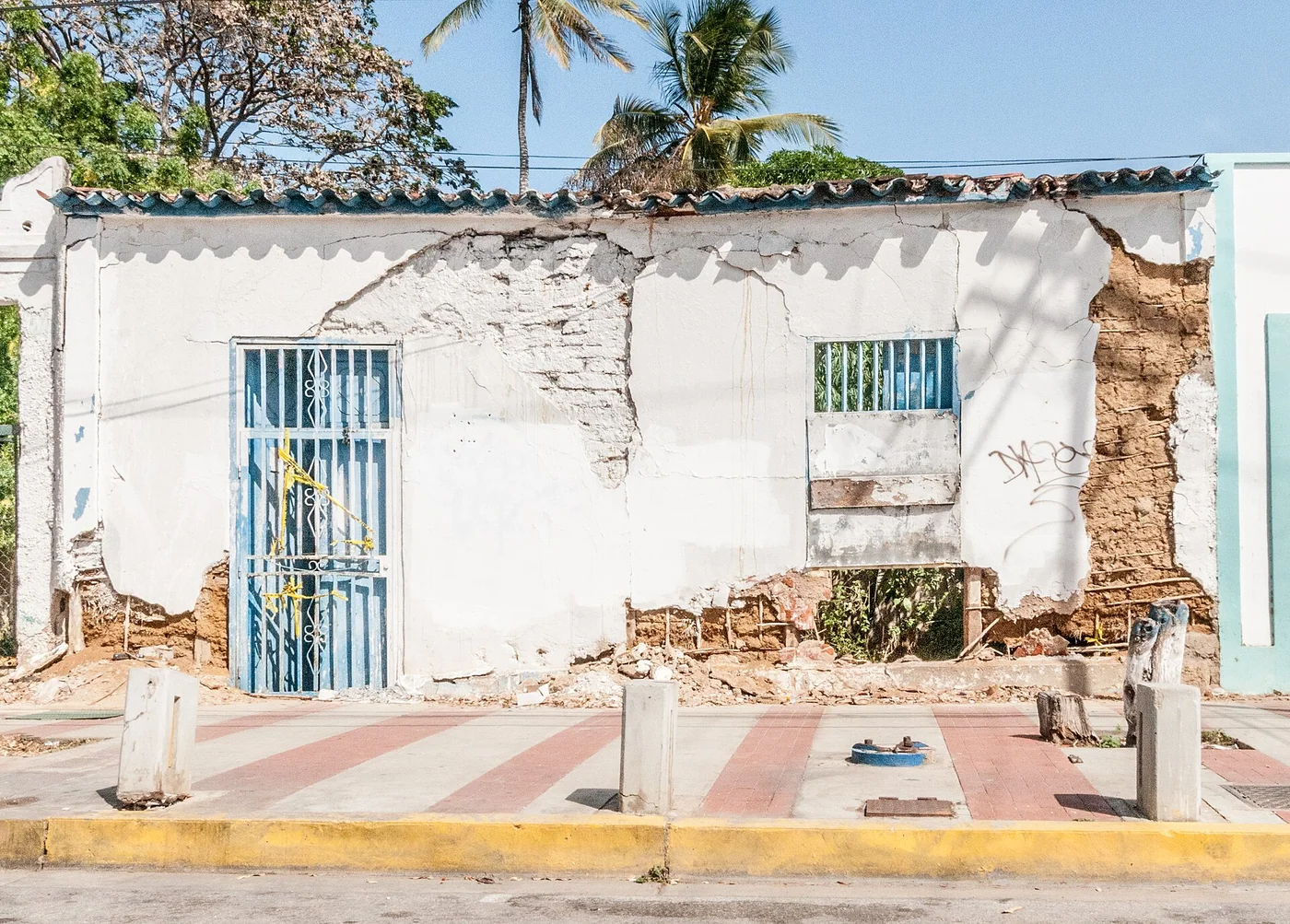Crumbling white house with exposed earthen wall in Pampatar, Margarita Island.
