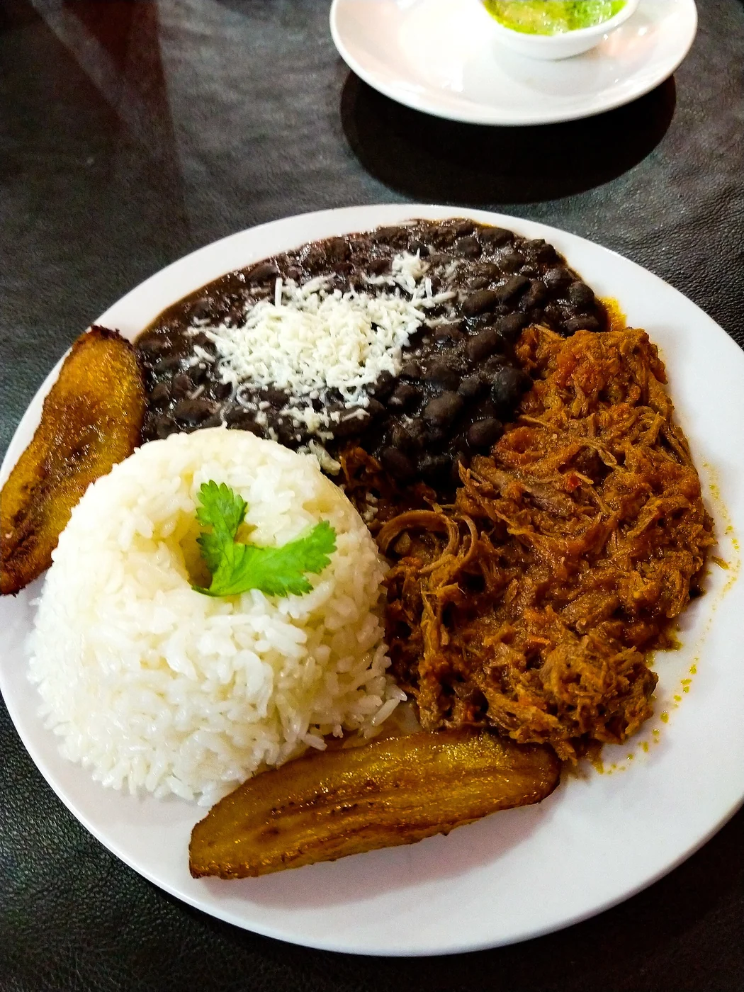 Pabellón Criollo: Caraotas negras con quello rallado, carne mechada, tajadas de platano y arroz.