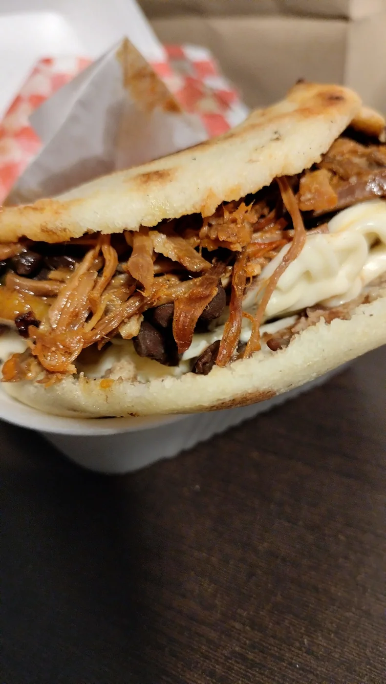 Arepa de carne mechada con frijoles negros y queso.