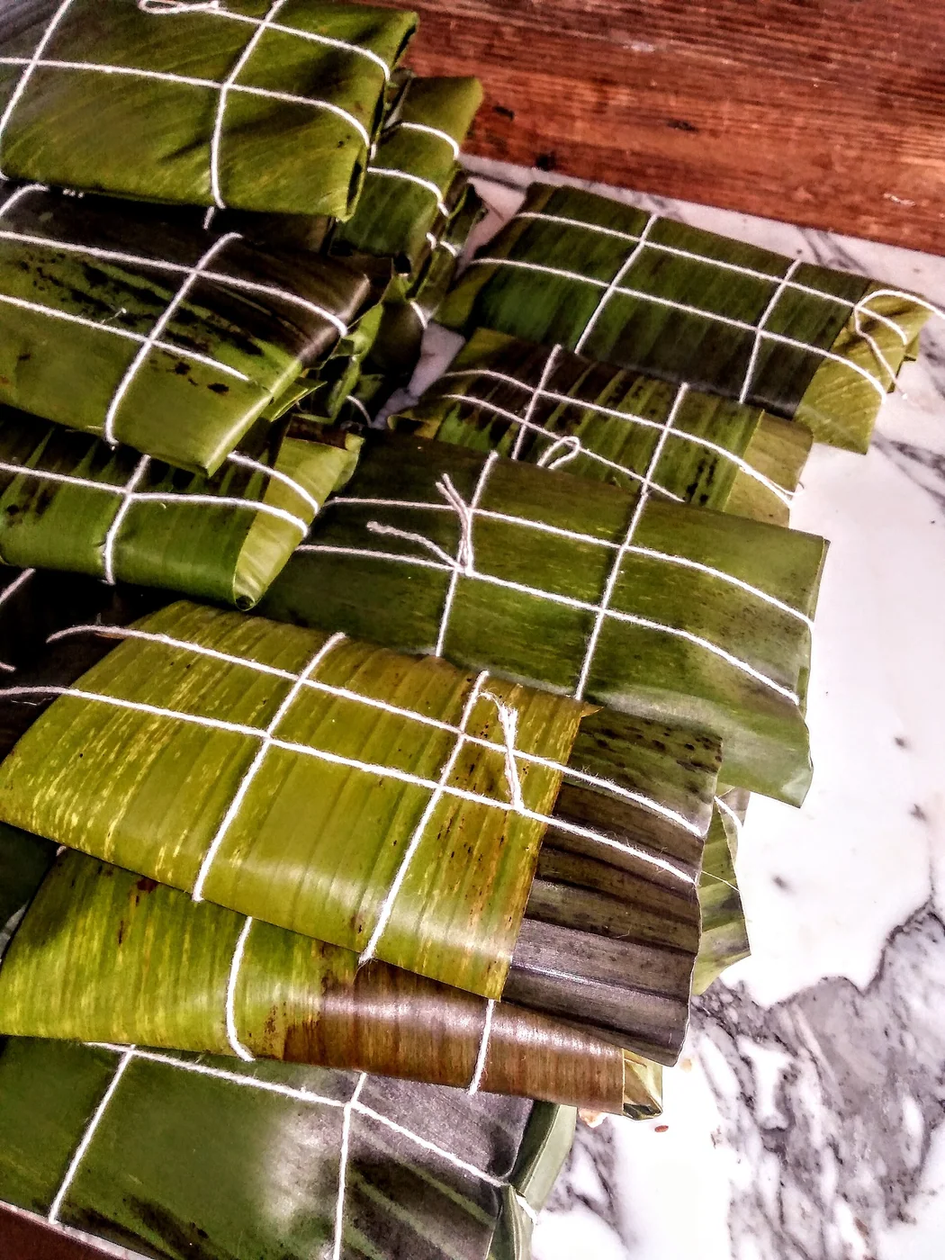 Food made with Corn Flour, olives, chicken meat, beef, raisins and vegetables in leaf of banana.