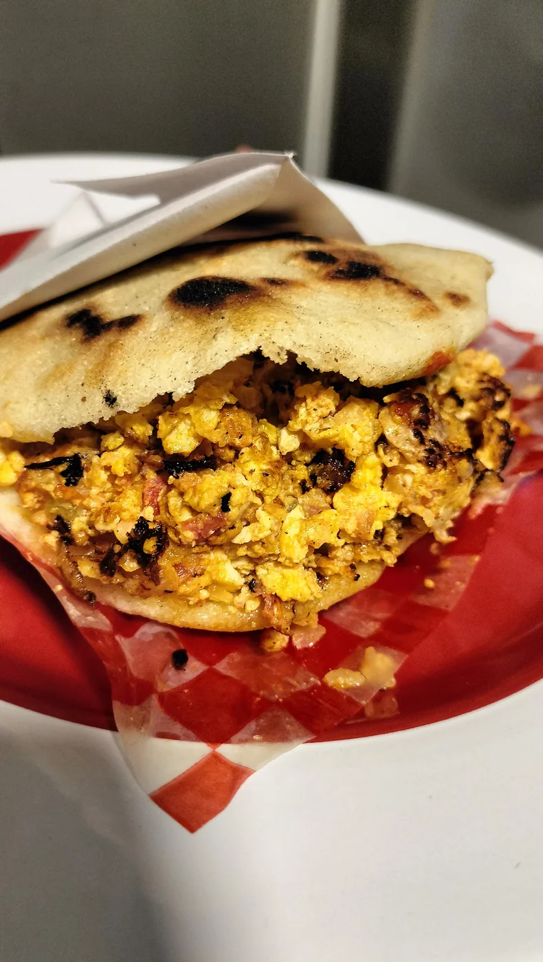 Arepa de huevo revuelto con jitomate y cebolla.